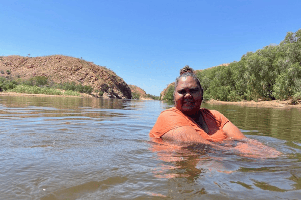 A woman stands in a river looking at the camera