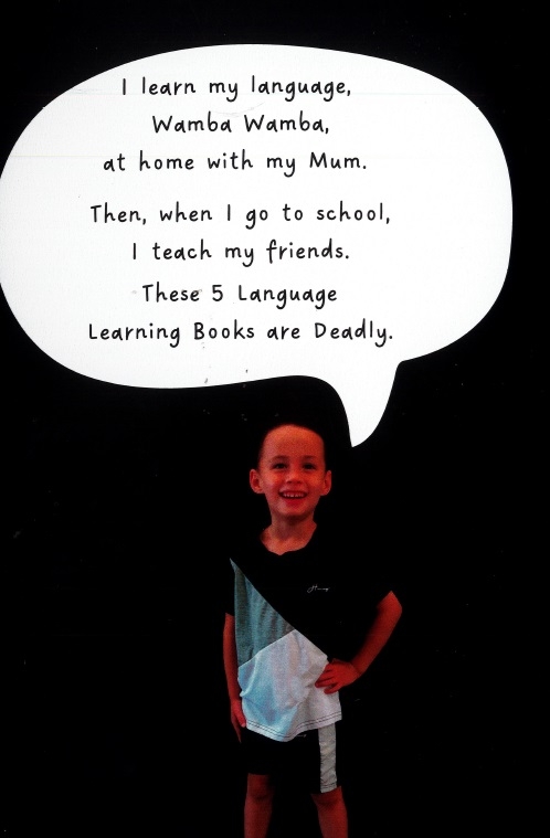 A young person stands with a hand on their hip against a black background. Above them is a speech bubble that reads 'I learn my language, Wamba Wamba, at home with my mum. Then, when I got to school, I teach my friends These 5 Language Learning Books are Deadly.'