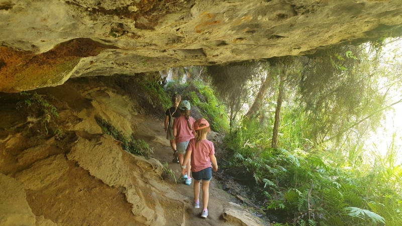 Two children walk beneath a rock overhang