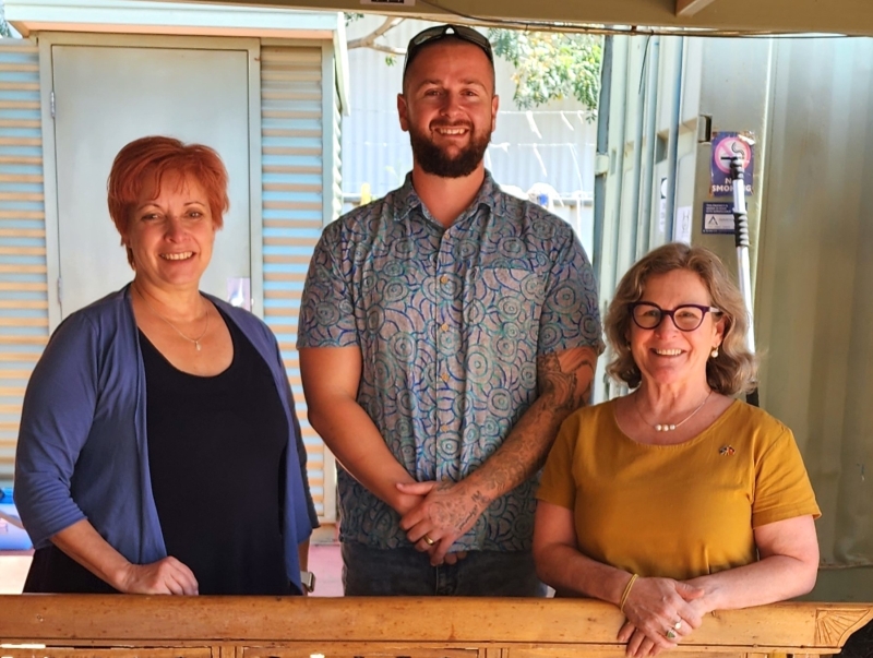 Three people - a man and 2 women - stand smiling at the camera