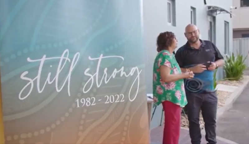 A banner reads 'still strong 1982-2022' and 2 people stand together next to it