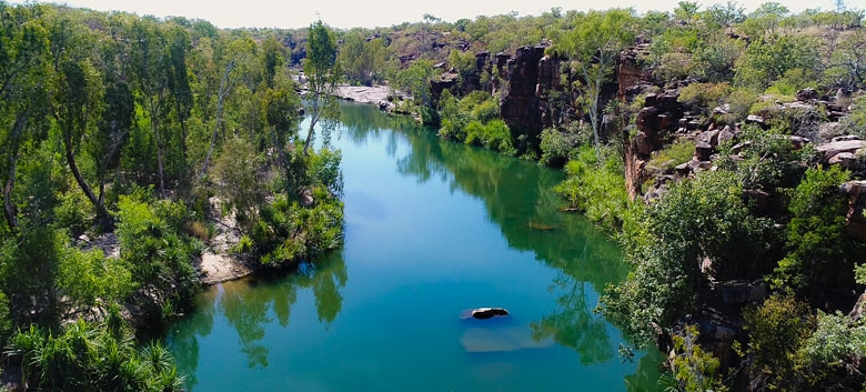 A blue river between rocky cliffs and green trees