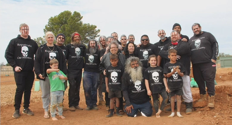 A group of people stand and kneel facing the camera