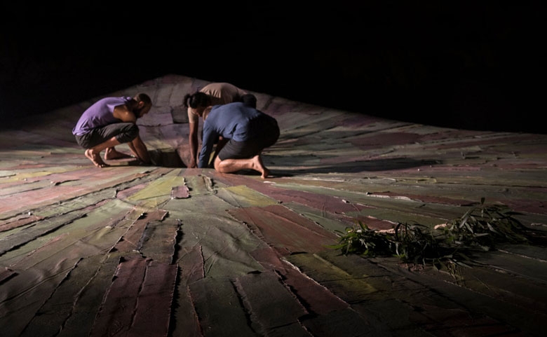 Three people crouch on a decorative floor