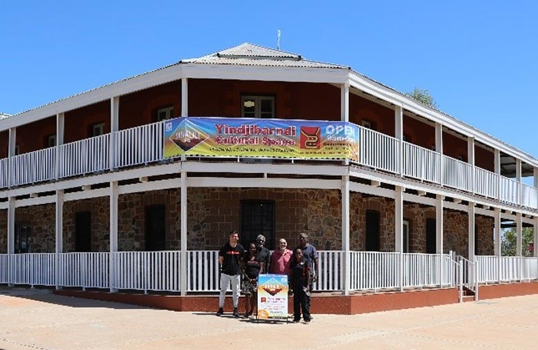 A small group of people stands in front of a large 2-storey building
