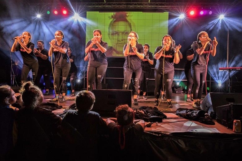 A group of people on a stage sing into microphones