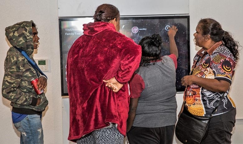 A small group of people touches a screen on a wall