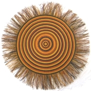 A round mat made with concentric circles in yellows and browns and a fringe around the edges
