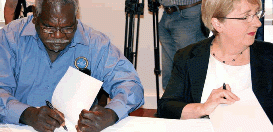 Two people sign paperwork at a table