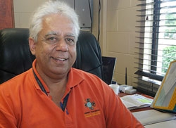 A man wearing an orange shirt sitting at a desk