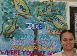 A woman stands next to a banner on which the word Pride can be read
