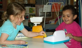 Two children play with a toy cash register