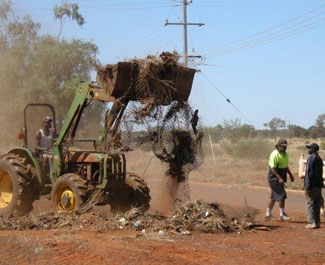 A front end loader lifts rubbish and dirt