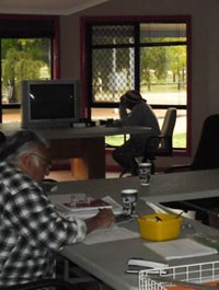 A dark room with people sitting at desks with paperwork