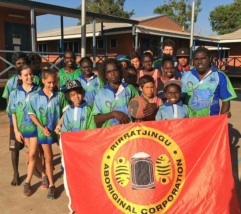 A group of children hold a banner saying Rirratjingu Aboriginal Corporation