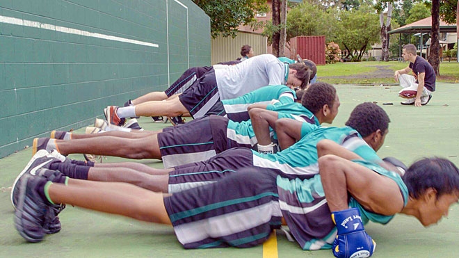 A line of people wearing boxing gloves and doing push ups