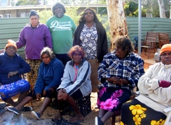 A group of people dressed in casual clothing sit and stand in an outdoor area