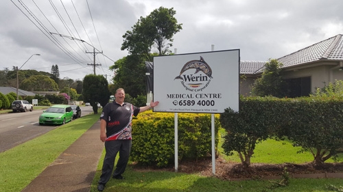 A man stands next to a sign that says Werin Medical Centre