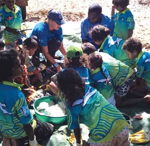 A group of children crowded together on a beach