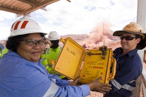 A woman and a man wearing hard hats and hi vs hold up a yellow object