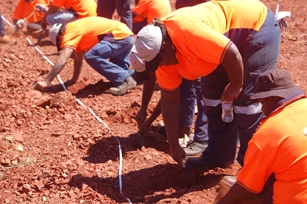 A group of people dressed in hi vis working in red dirt