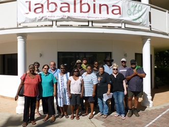 A group of people stands outside an office building. Above them is a banner with the word Jabalbina