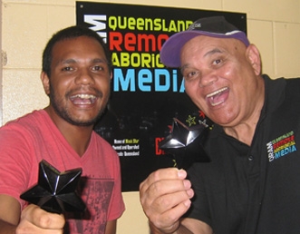 Two men smile and hold awards towards the camera