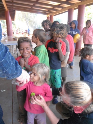 Children lining up as an older person hands food to the child in the front