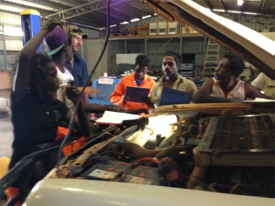 A group of young people around a car engine