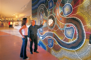 A man and a young woman stand next to a large mural