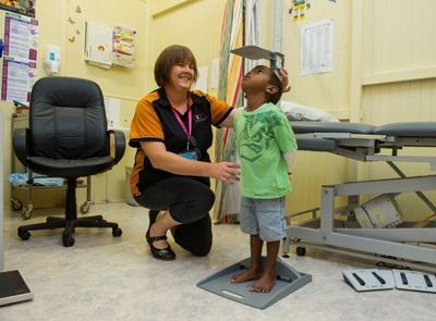A woman is measuring the height of a young child