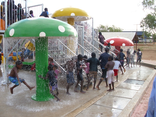 Children play under colourful mushroom structures that have water cascading down from them