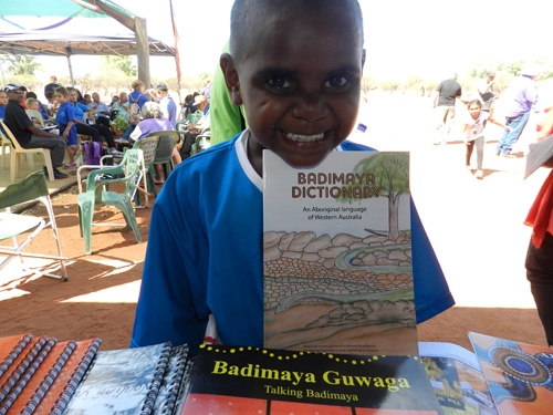 A close up of a child holding a book titled 'Badimaya Dictionary'