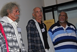 Three men in casual clothes stand in a room
