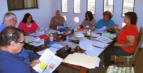 A group of people sit around a table covered in paperwork