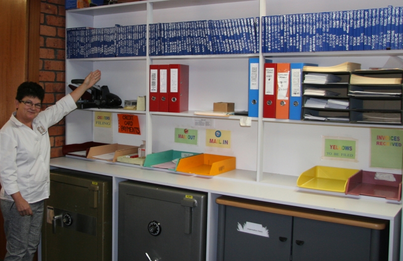 A woman poses next to neatly arranged shelving