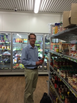 A man stands next to a shelf stocked with groceries
