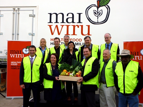 A large group of people wearing hi vis pose in front of a truck with mai wiru on it