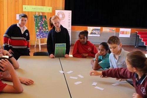 Schoolchildren work on an activity with pieces of paper at a large table