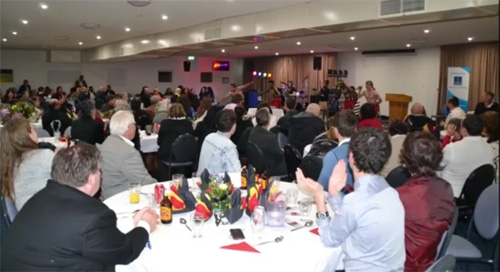 People sit at round tables in a function room